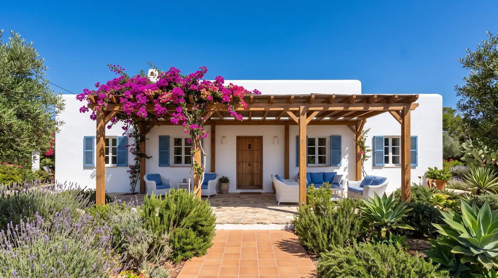 Fachada blanca de una villa con porche de madera, buganvilla y jardín mediterráneo (imagen ilustrativa)